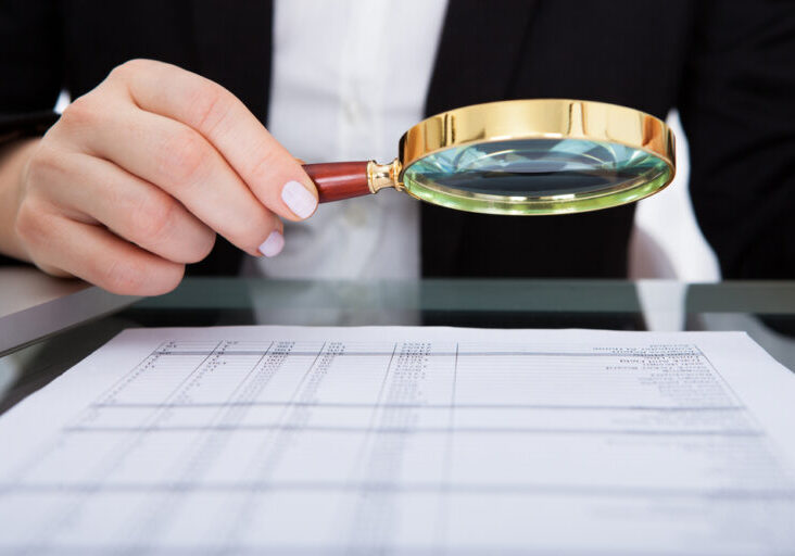 Businesswoman,Looking,At,Document,Through,Magnifying,Glass